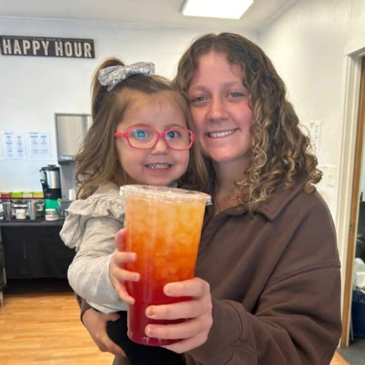 A guest holding a little girl and a big sunrise loaded tea during happy hour